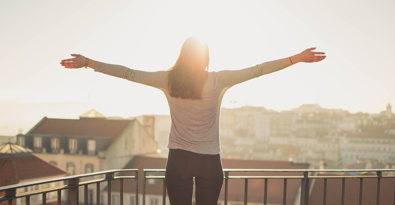 An introvert arms open wide on a balcony look out onto the worldwaiting suggesting they are thriving and happy