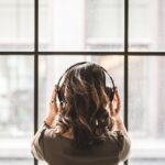 a introvert facing a large window with noise cancelling headphones on interpreting the joy being able to work in silence