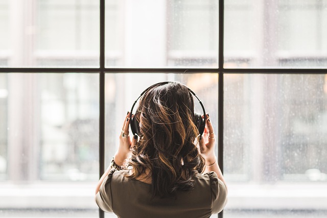 a introvert facing a large window with noise cancelling headphones on interpreting the joy being able to work in silence